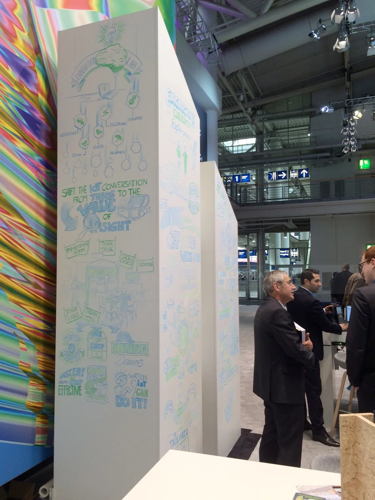 People standing near a booth with abstract artwork and colorful patterns by Alexander Roncaldier