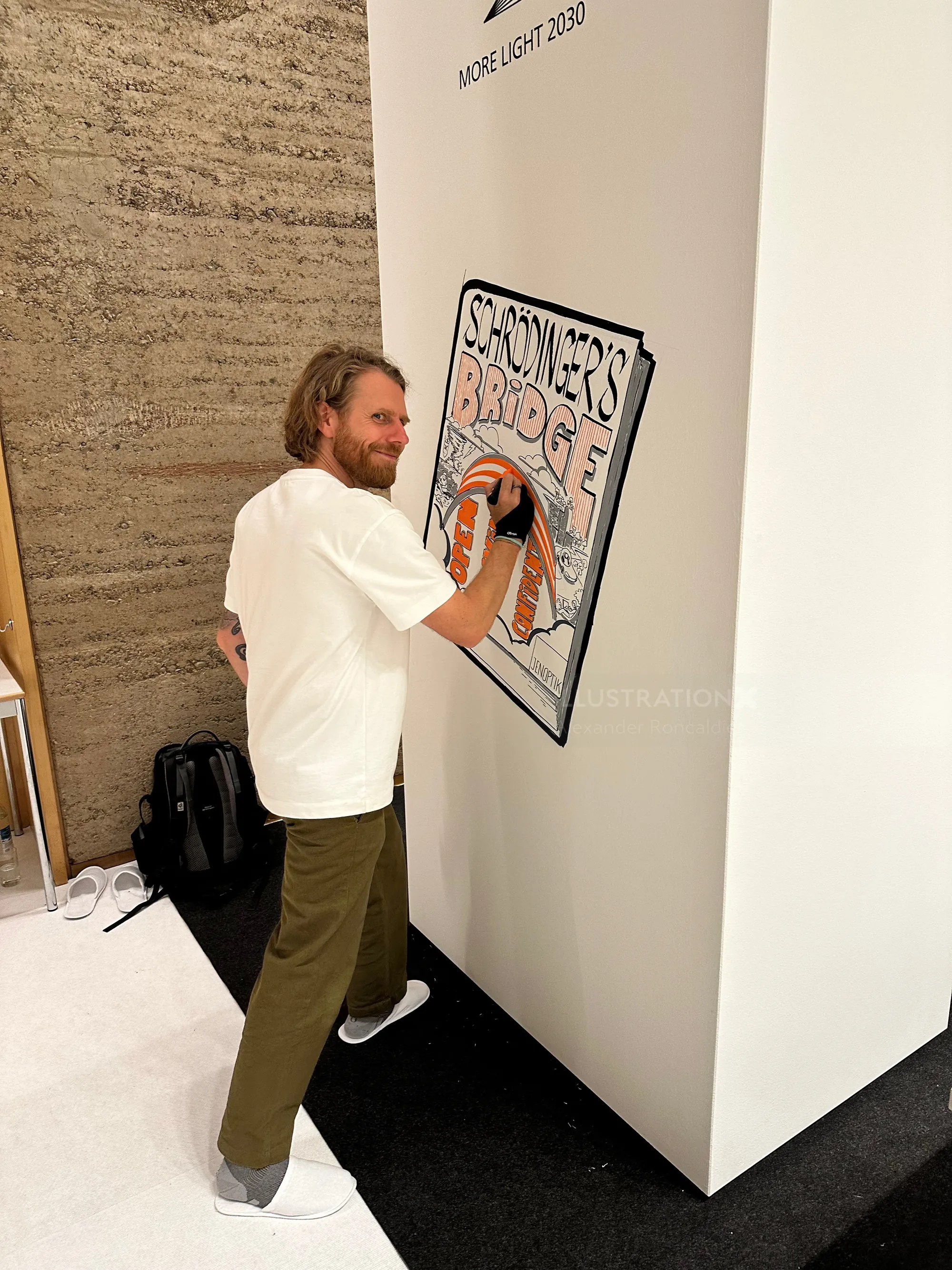 Man creating artwork on a white wall featuring the text Show Me's Broke