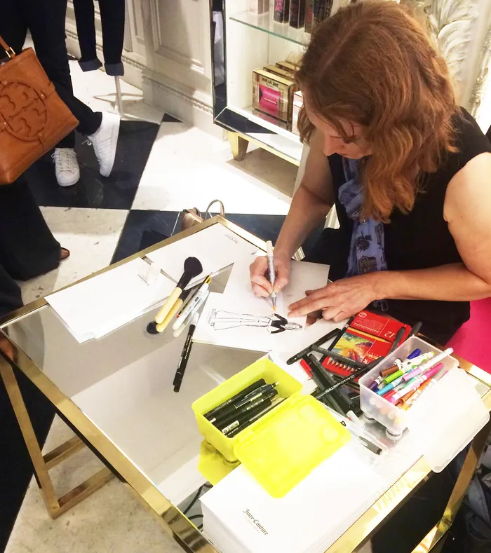 Woman drawing at a table with art supplies and tools