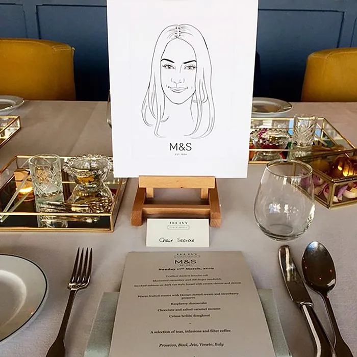Line art portrait on easel with table setting at The Ivy