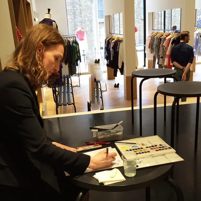 Artist drawing at a table in a clothing store