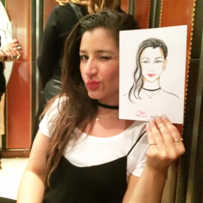 Woman holding a live portrait sketch and winking