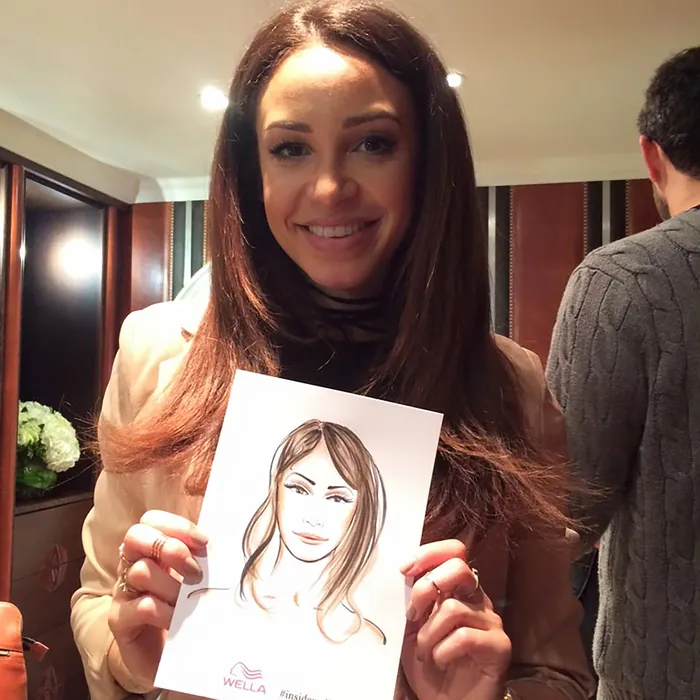Woman holding a portrait drawing of herself at an event