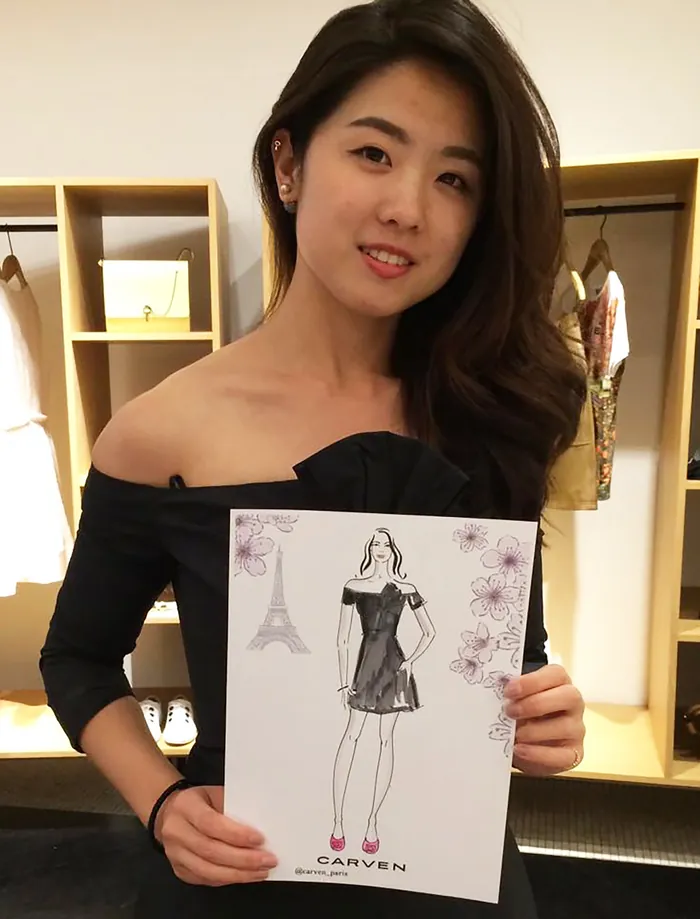 Woman holding fashion sketch at live event in stylish setting