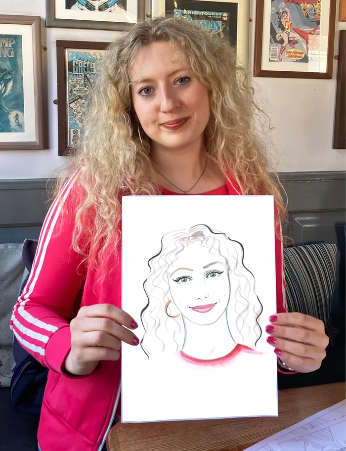 Woman holding a live portrait drawing of herself