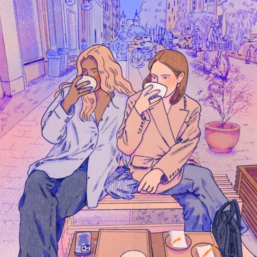 Two women drinking coffee at an outdoor café in the city