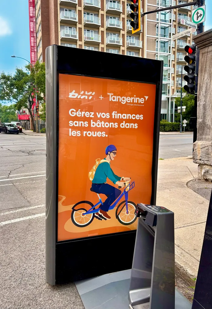 Illustration of a person riding a bike on an orange Tangerine Bank ad