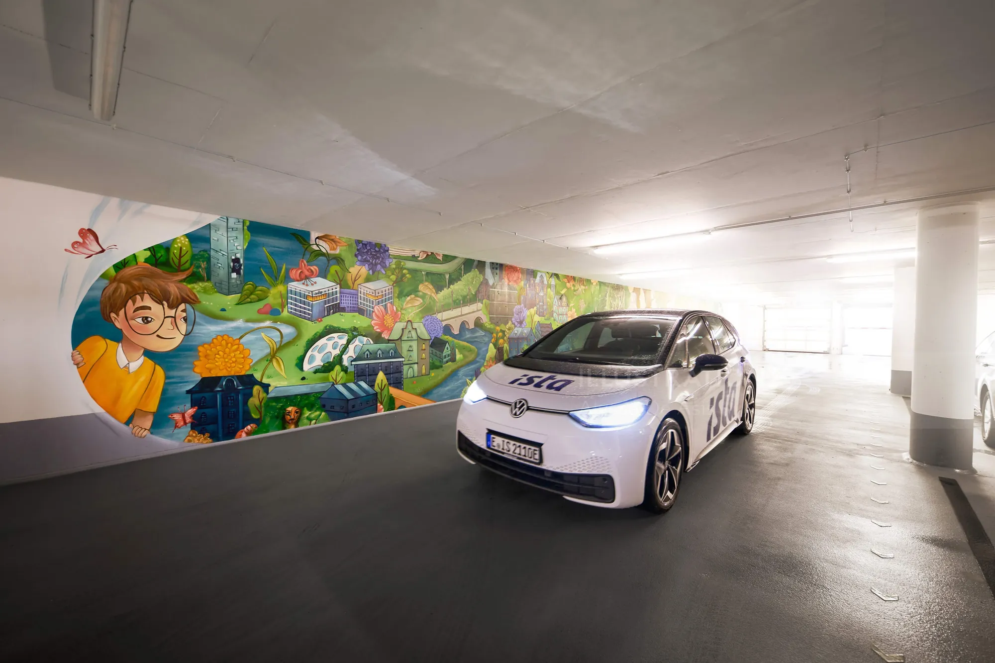 Coche eléctrico en aparcamiento subterráneo con mural colorido de Alyssa De Asis