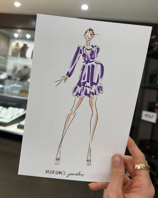 Hand holding a fashion illustration of a woman in a purple dress
