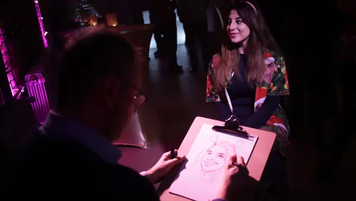 Artist drawing a woman's portrait in a dark room with purple lights