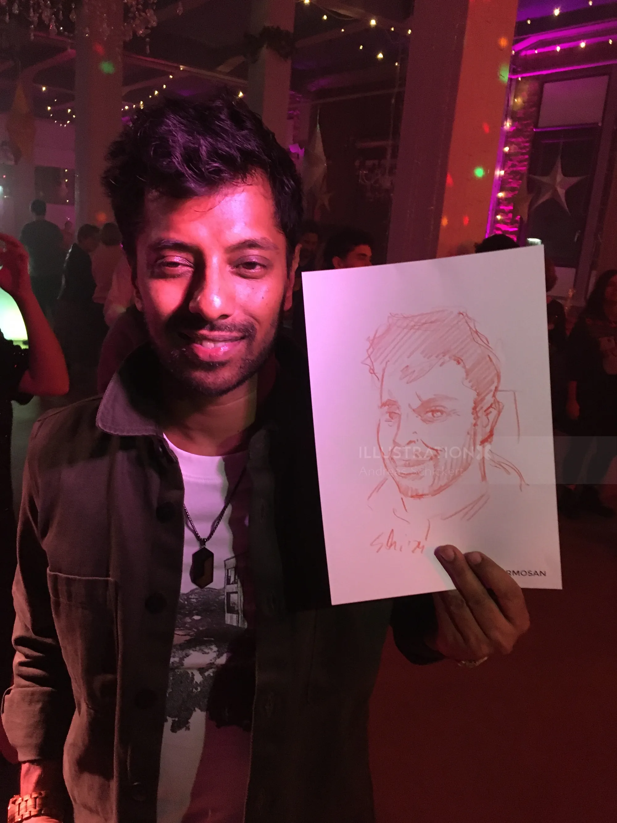 Man holding a caricature drawing at a colorful party