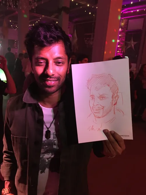 Man holding a caricature drawing at a colorful party