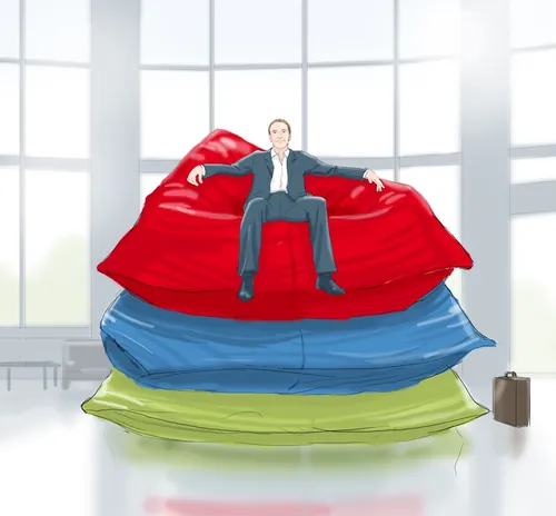 Man in suit sitting on stacked red, blue, and green bean bags by Andreas Schickert