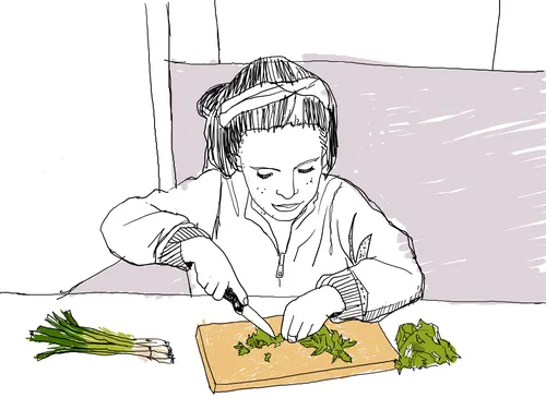 Child with headphones chopping herbs on cutting board by Andreas Schickert