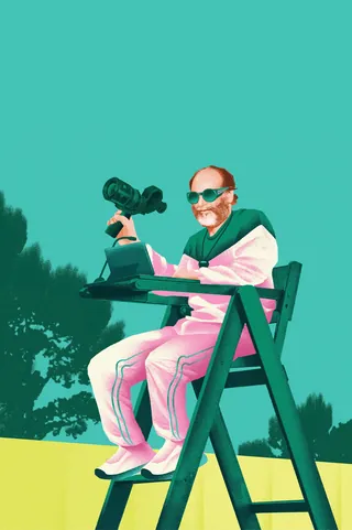 Man in pink tracksuit on tall chair with camera and laptop