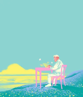Man sitting at a desk writing near water at sunrise