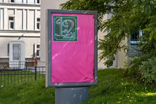 Outdoor billboard showing bright pink poster with green and white graphic by Andrei Nicolescu