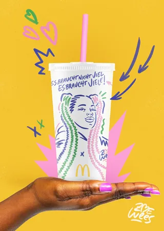 Hand holding decorated McDonald's cup with colorful drawings and German text