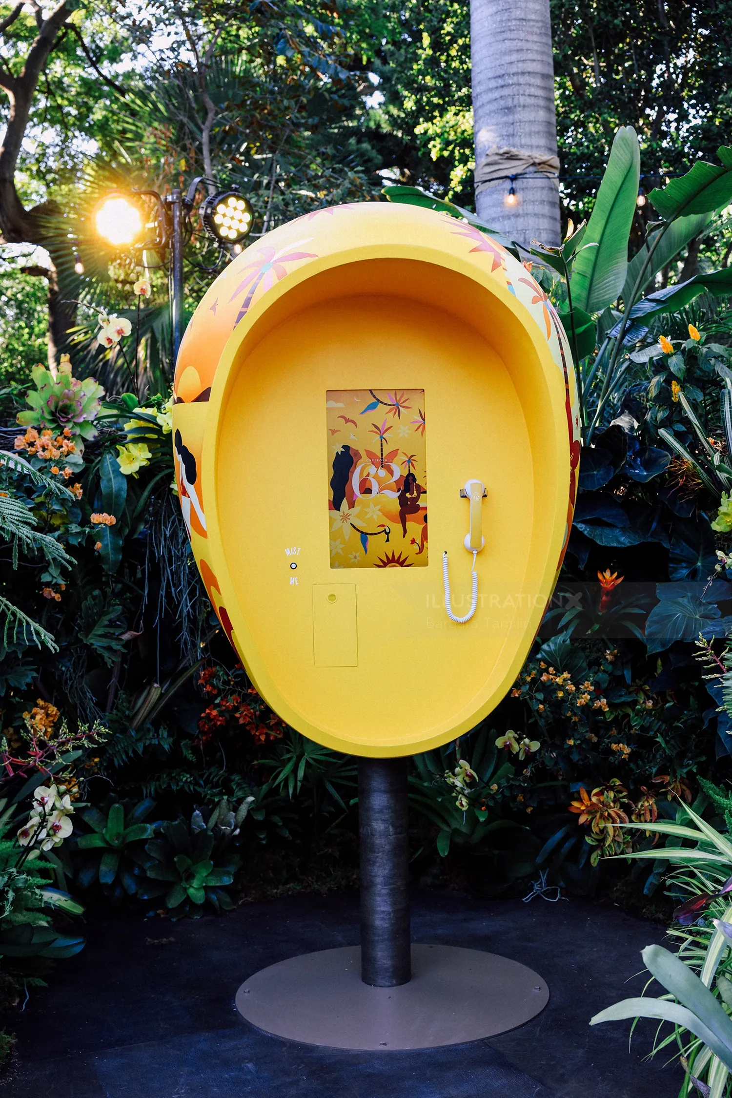 Yellow ear-shaped phone booth in lush green garden