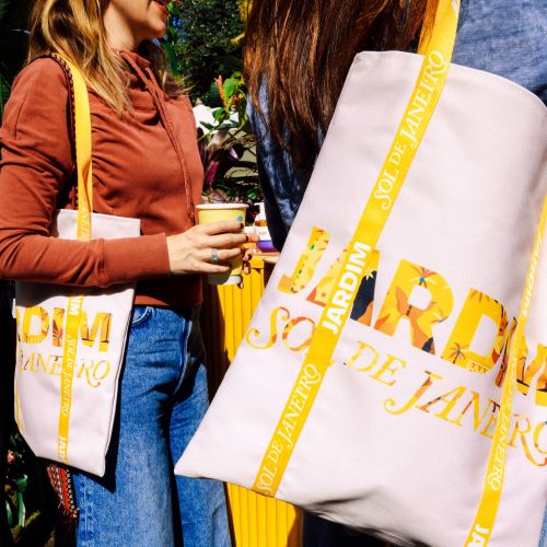 Women holding white tote bags with yellow Rio de Janeiro design