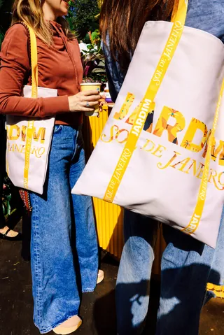 Women holding white tote bags with yellow Rio de Janeiro design