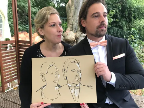 Man and woman holding caricature drawing by Björn von Schlippe