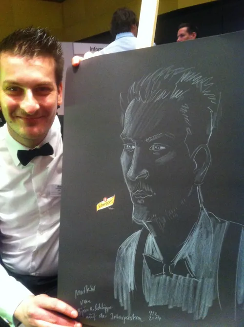 Man in tuxedo holds chalk portrait drawing on blackboard by Björn von Schlippe