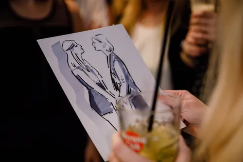Person holding drink and looking at caricature sketch by Björn von Schlippe