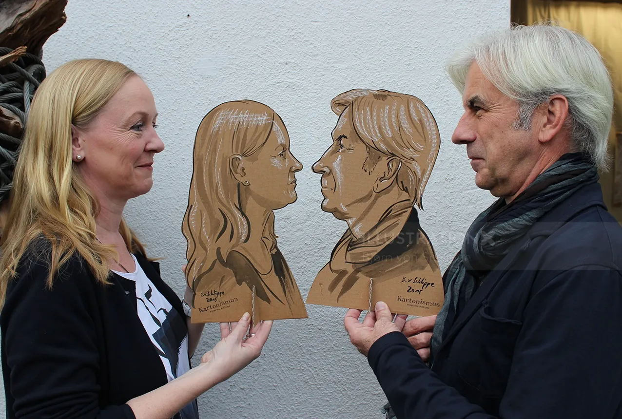 Two people holding wooden silhouette portraits of each other by Björn von Schlippe