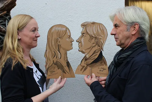 Two people holding wooden silhouette portraits of each other by Björn von Schlippe