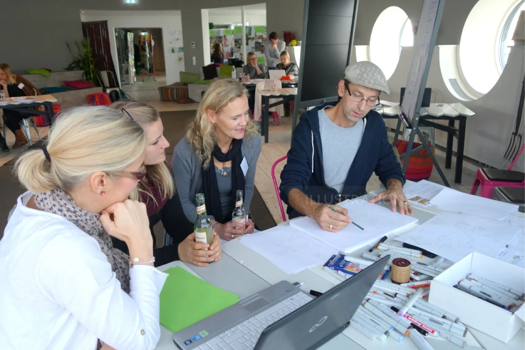 Four people collaborate on documents in a bright modern office by Björn von Schlippe