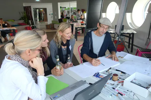 Four people collaborate on documents in a bright modern office by Björn von Schlippe