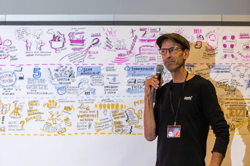 Man with microphone presenting in front of whiteboard covered with sketches