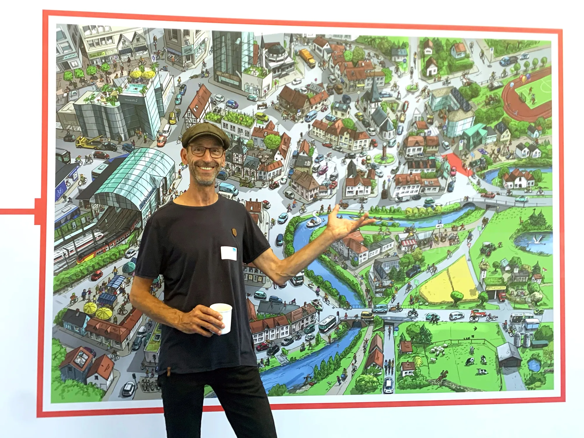 Man standing next to large colorful illustrated town map.