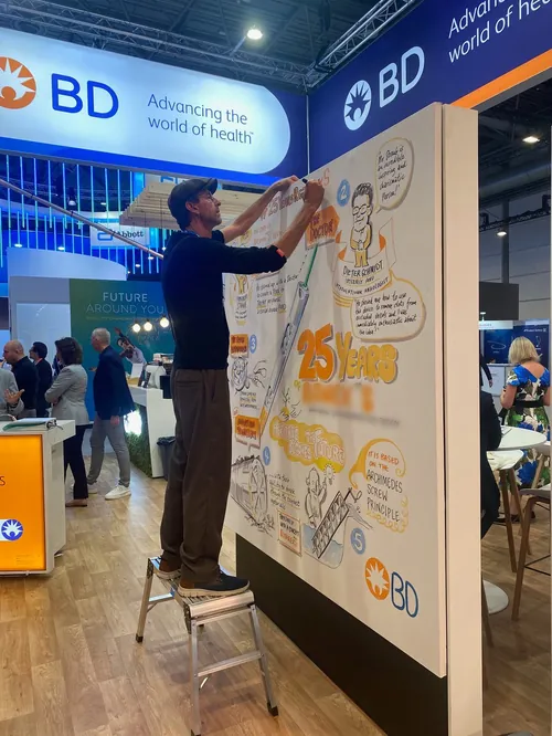 Man drawing on large poster at BD health event booth