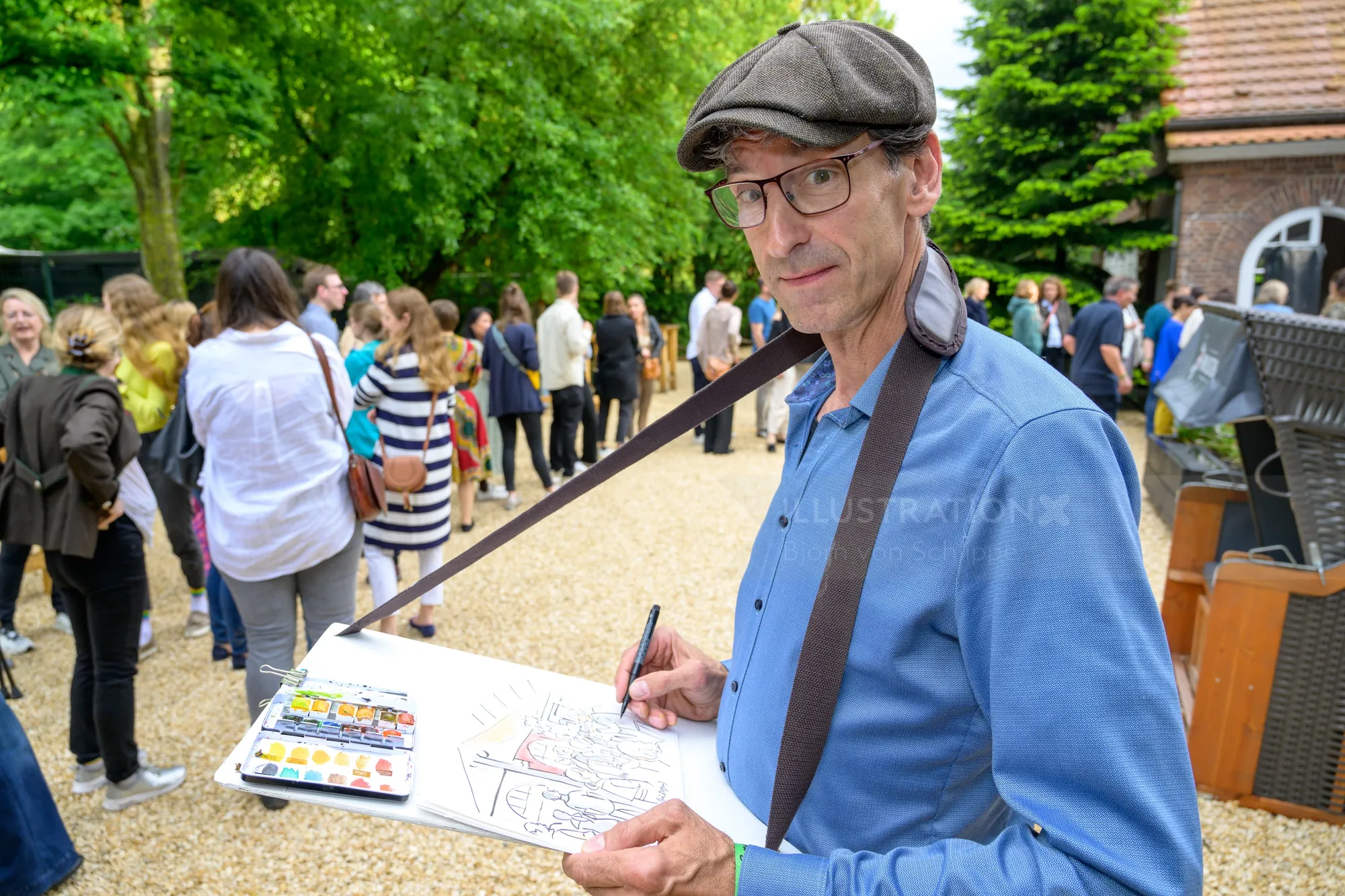 Male artist sketching outdoors with people gathered behind him