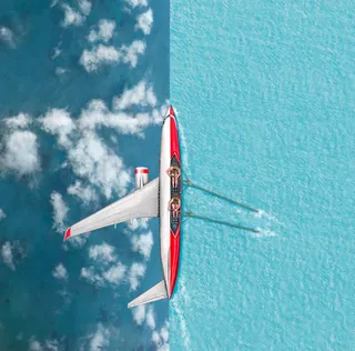 Aerial image of rowing team in red boat on water by Bob Venables