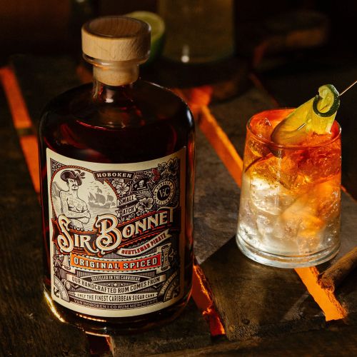 Bottle of Sir Bonnet original spiced rum next to a cocktail glass with lime garnish