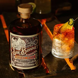 Bottle of Sir Bonnet original spiced rum next to a cocktail glass with lime garnish