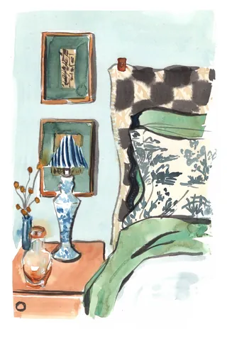 Bedroom corner with decorative pillow, blue lamp, and framed pictures