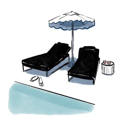 Poolside lounge chairs under umbrella with sandals and drinks by Briana Kranz