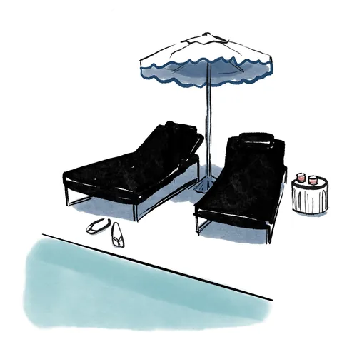 Poolside lounge chairs under umbrella with sandals and drinks by Briana Kranz