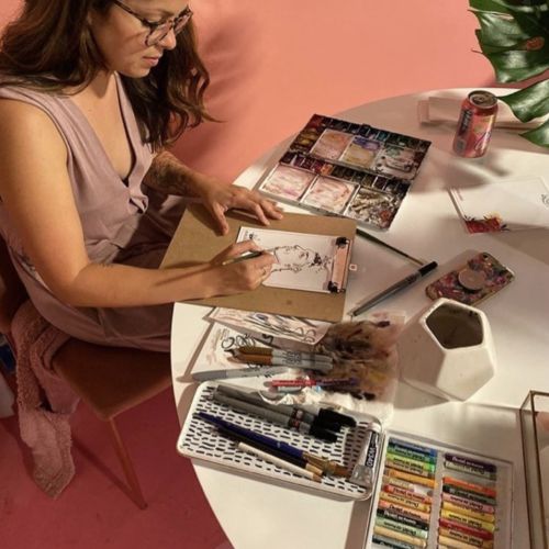 Woman drawing with art supplies at a table by Briana Kranz