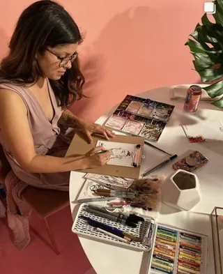 Woman drawing with art supplies at a table by Briana Kranz