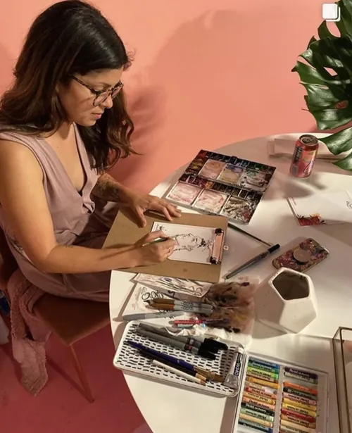 Woman drawing with art supplies at a table by Briana Kranz