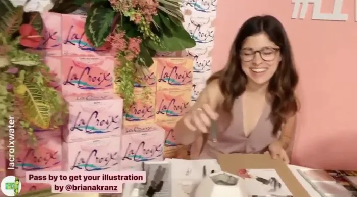 Woman artist drawing at live event with LaCroix cans and plants background by Briana Kranz