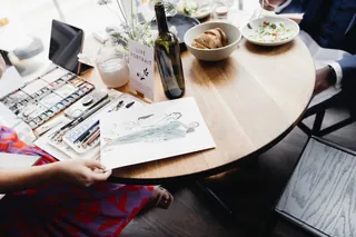 Fashion sketch and watercolor paints on round table by Briana Kranz Live Event Drawing