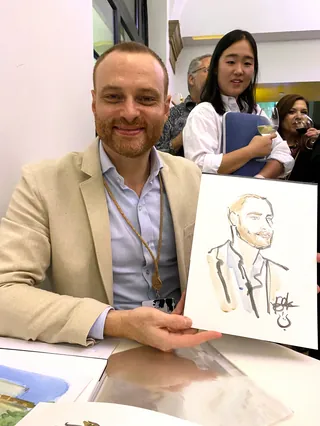 Man in beige blazer holding a quick portrait sketch