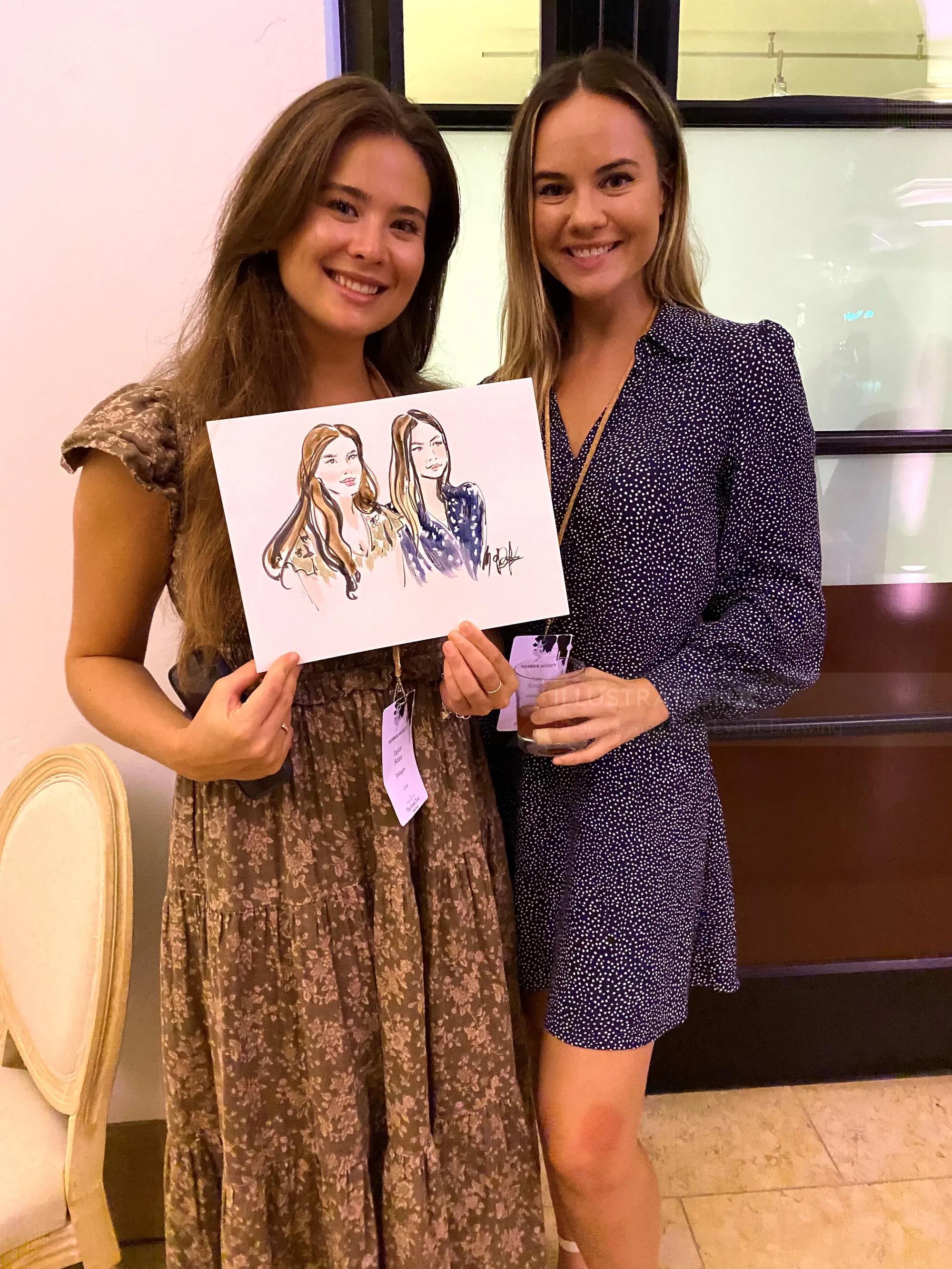 Two women smiling holding a portrait sketch between them