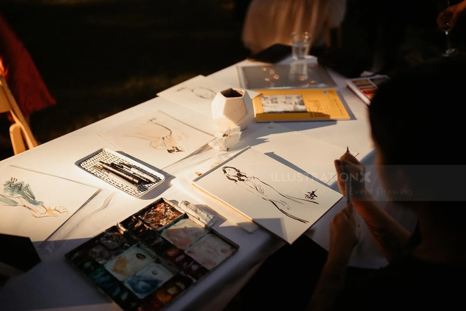 Wedding portraits and sketches displayed on a table with warm lighting